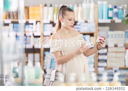 Pregnant woman customer choosing paracetamol in drugstore 126149352