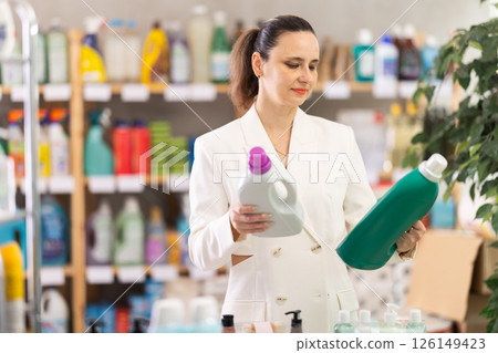 Adult woman buyer chooses detergent in store Adult woman buyer chooses detergent in store 126149423