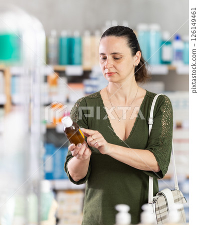 Middle-aged woman customer choosing syrup in drugstore 126149461