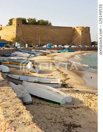 Medina of Hammamet on Mediterranean coast in Tunisia. Ancient fortress and fishing boats on beach Medina of Hammamet on Mediterranean coast in Tunisia. Ancient fortress and fishing boats on beach 126149538