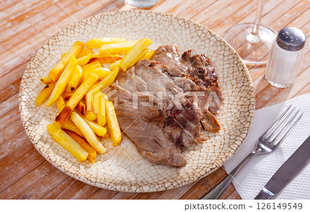Baked pork chops on bone served with french fries 126149549
