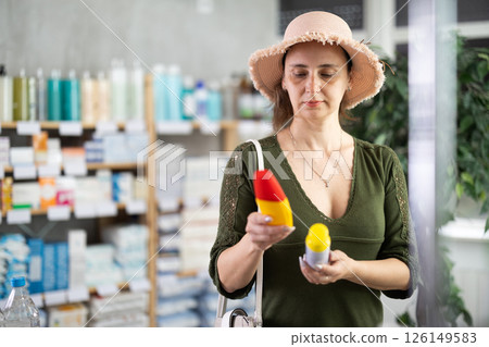 Middle-aged woman choosing repellent in chemist's shop Middle-aged woman choosing repellent in chemist's shop 126149583