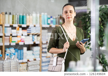 Woman with phone and electronic prescription in drugstore Woman with phone and electronic prescription in drugstore 126149604