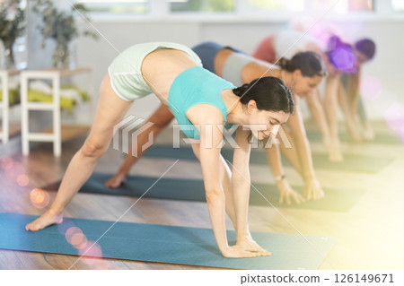 Young girl teaches yoga lesson, shows students technique of performing Parshvottanasana asana 126149671