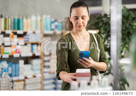 Middle-aged woman scanning pill package Middle-aged woman scanning pill package 126149673