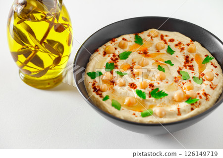 hummus in bowl and bottle with olive oil with chickpeas and spices close-up, selective focus hummus in bowl and bottle with olive oil with chickpeas and spices close-up, selective focus 126149719