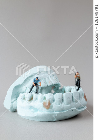 Miniature Workers Cleaning Teeth on Dental Mold 126149791