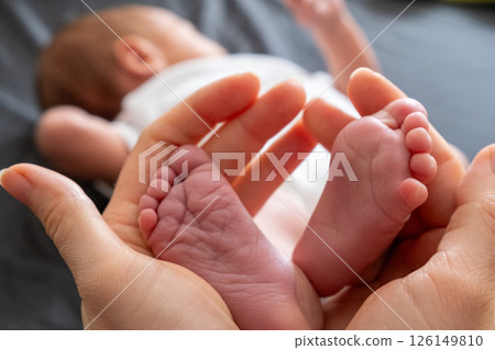Tender Moment: Adult Hands Holding Newborn Baby Feet 126149810