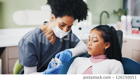 Dentist, girl and mold with teaching for oral wellness, care and listening to advice at hospital. Woman, child and dental model for learning, talk and consultation for health services at clinic Dentist, girl and mold with teaching for oral wellness, care and listening to advice at hospital. Woman, child and dental model for learning, talk and consultation for health services at clinic 126150051