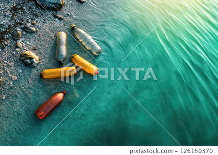 Colorful plastic bottles floating on the shore of a tranquil water body with pebbles and sunlight 126150370