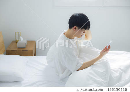 A man who uses smartphones in bed A man who uses smartphones in bed 126150516