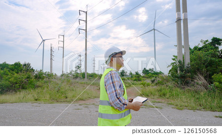 Engineer working with laptop at wind turbine field generating electricity for renewable clean energy 126150568