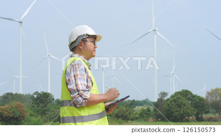 Engineer working with laptop at wind turbine field generating electricity for renewable clean energy 126150573