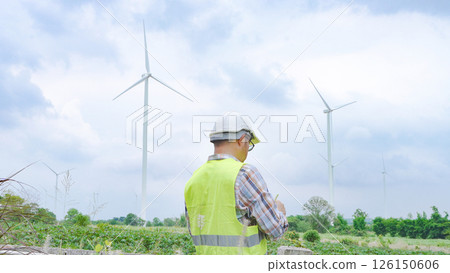 Engineer working with laptop at wind turbine field generating electricity for renewable clean energy 126150606