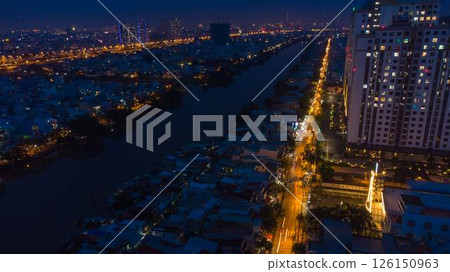 Aerial view of illuminated church by river surrounded by high rise residential buildings and city streets during blue hour with urban skyline and canal cityscape at twilight. High quality photo Aerial view of illuminated church by river surrounded by high rise residential buildings and city streets during blue hour with urban skyline and canal cityscape at twilight. High quality photo 126150963