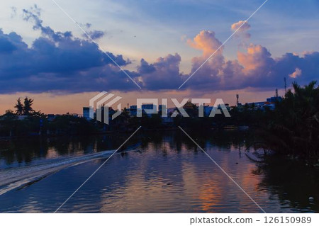 Towering cumulus clouds glowing in golden sunlight against clear blue sky at sunset with dramatic natural cloudscape and atmospheric light. High quality photo 126150989