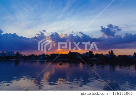 Towering cumulus clouds glowing in golden sunlight against clear blue sky at sunset with dramatic natural cloudscape and atmospheric light. High quality photo 126151005