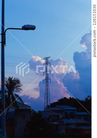 Towering cumulus clouds glowing in golden sunlight against clear blue sky at sunset with dramatic natural cloudscape and atmospheric light. High quality photo 126151030