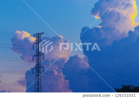 Towering cumulus clouds glowing in golden sunlight against clear blue sky at sunset with dramatic natural cloudscape and atmospheric light. High quality photo 126151031