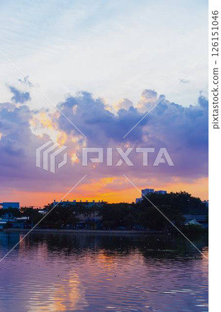 Towering cumulus clouds glowing in golden sunlight against clear blue sky at sunset with dramatic natural cloudscape and atmospheric light. High quality photo 126151046