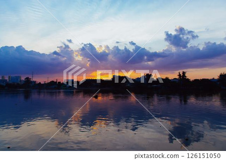 Towering cumulus clouds glowing in golden sunlight against clear blue sky at sunset with dramatic natural cloudscape and atmospheric light. High quality photo 126151050