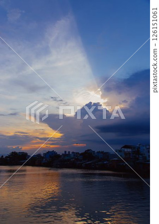 Stunning pink and purple sunset sky reflecting on calm river with silhouetted city skyline and peaceful twilight atmosphere in urban landscape at dusk. High quality photo 126151061
