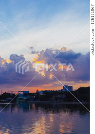 Towering cumulus clouds glowing in golden sunlight against clear blue sky at sunset with dramatic natural cloudscape and atmospheric light. High quality photo 126151067