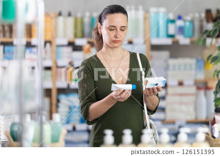 Woman in cardigan choosing ointment at pharmacy 126151395