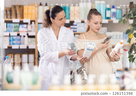 Pregnant woman buyer scans cream qr code with woman pharmacist Pregnant woman buyer scans cream qr code with woman pharmacist 126151398