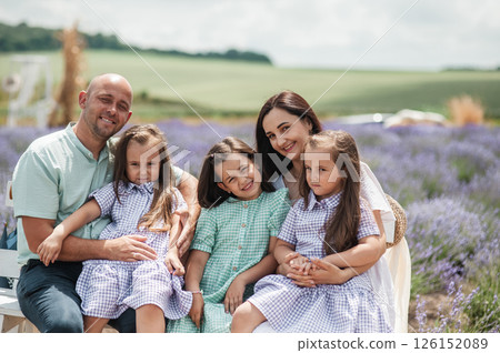In the middle of a lavender field, a family is spending a cozy moment together. In the middle of a lavender field, a family is spending a cozy moment together. 126152089