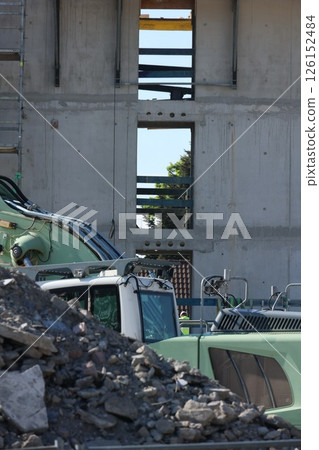 A green construction truck is parked next to a pile of rocks A green construction truck is parked next to a pile of rocks 126152484