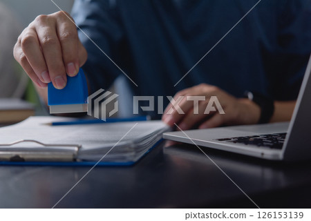 Business administration, office employee stamping paperwork, official document processing, contract approval system, business compliance, certification process, document verification. Business administration, office employee stamping paperwork, official document processing, contract approval system, business compliance, certification process, document verification. 126153139