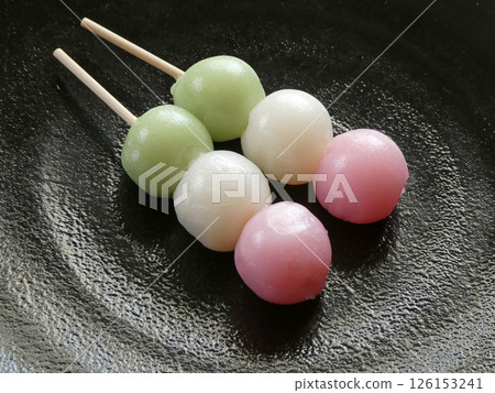 A photo of three-colored dumplings, representing the pink of cherry blossoms in spring, the green of fresh greenery in summer, and the white of snow in winter. 126153241