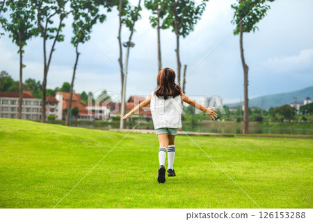 A cute and happy little girl is playing and running around the park on a beautiful morning. A cute and happy little girl is playing and running around the park on a beautiful morning. 126153288