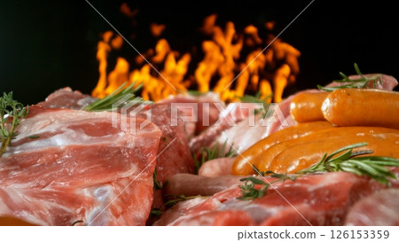 Large assortment of premium raw meat, beef, sausages, pork and chicken suitable for butchery advertising, fire on background 126153359