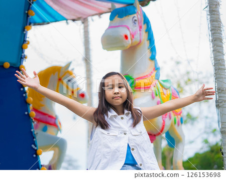Asian girl having fun in amusement park, enjoying carousel on family vacation. 126153698