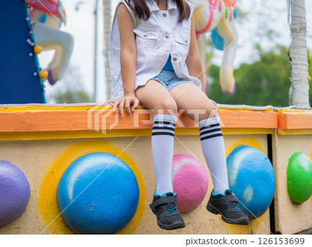 Asian girl having fun in amusement park, enjoying carousel on family vacation. 126153699