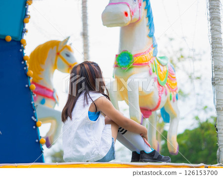 Asian girl having fun in amusement park, enjoying carousel on family vacation. 126153700