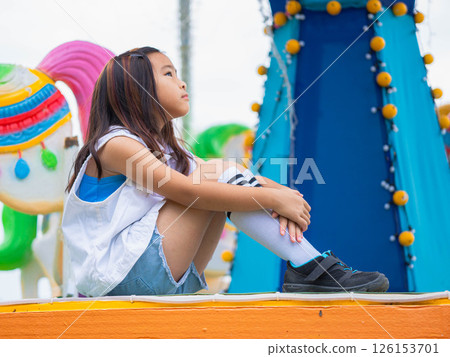 Asian girl having fun in amusement park, enjoying carousel on family vacation. 126153701
