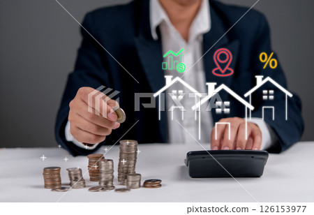 Businessman calculating home investment with coins and financial property icons, symbolizing real estate finance, savings, and mortgage planning. ROI, home loan. 126153977
