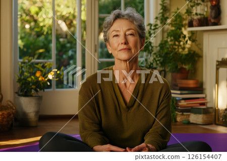 Middle-aged woman with gray hair practicing relaxation at home with natural light 126154407