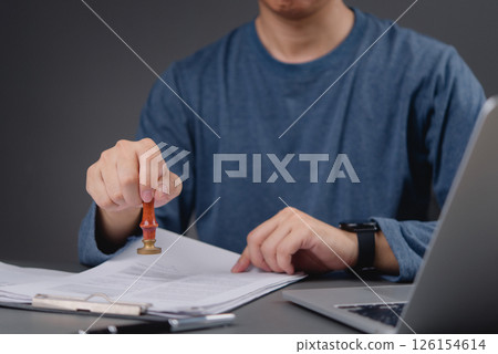 professional office worker using a stamp on paperwork, demonstrating the administrative process and the formal approval of documents. 126154614