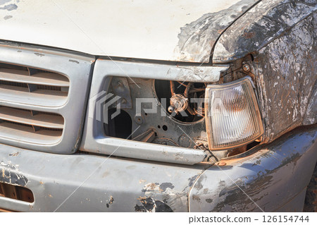 Broken light cover and scratched front paint and metal on SUV all terrain vehicle, dirty from red desert dust Broken light cover and scratched front paint and metal on SUV all terrain vehicle, dirty from red desert dust 126154744