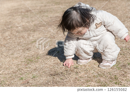 [相模原市立麻溝公園，一名一歲兒童蹲在草地上玩耍] 126155082