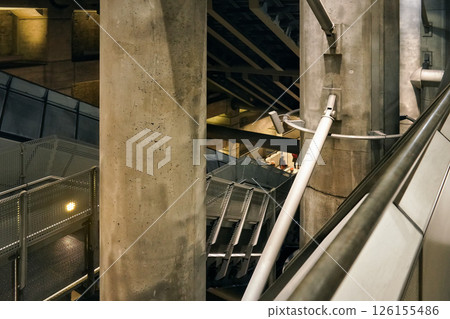 Concrete & steel walls and tubes in Westminster underground train station, blurred people walking down stairs in distance - futuristic architecture 126155486
