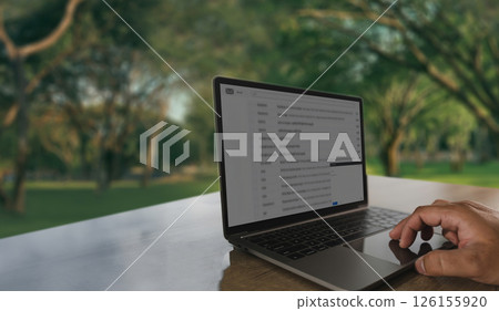Business man working remote workperson using laptop outdoors wooden table with blurred green park background, working or browsing emails 126155920