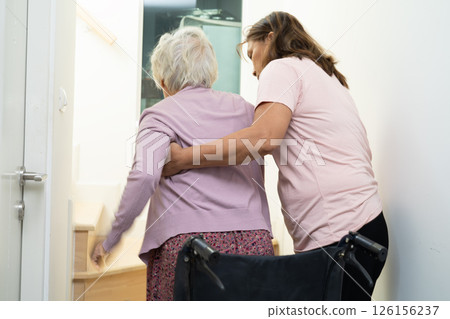 Caregiver help asian or elderly old woman sitting wheelchair support up the stairs in home. 126156237
