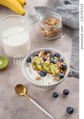 Natural yogurt with granola, kiwi and blueberries in a bowl on a light background with fresh berries Natural yogurt with granola, kiwi and blueberries in a bowl on a light background with fresh berries 126156328