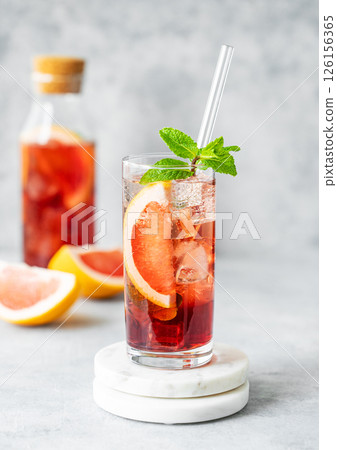 Refreshing cocktail with grapefruit, mint and ice in a glass on a table with bottle  126156365
