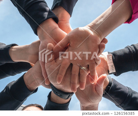 hand on hA symbolic image of hands stacked on top of each other, symbolizing teamwork, unity, and collaboration. The close-up composition highlights the diversity and collective strength of a group 126156385